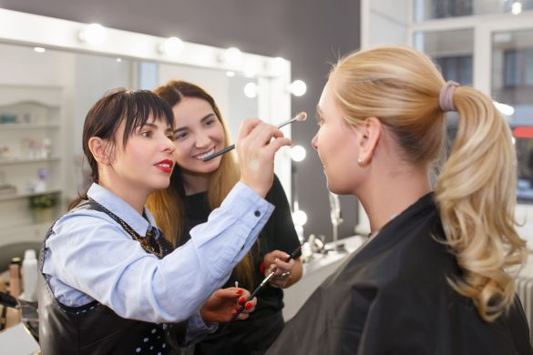 Two women are doing a client's makeup